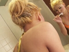 Sultry blonde shemale in a tantalizing orange bikini pleasures herself in the bathtub