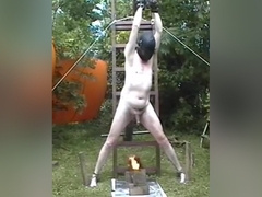 Chained naked male slave gets his cock and balls roasted