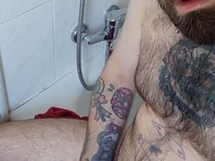 Bearded hunk strokes his massive cock after a steamy shower