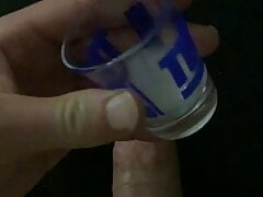 Hung jock cums into shot glass and pours on cock