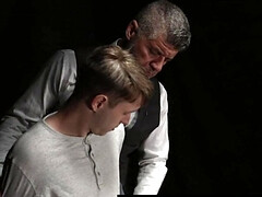 Beefy man in a suit is examining a shy blond fellow