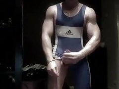 Muscled wrestler stroking big uncut cock in singlet