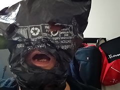 man sucking cucumber with head in garbage bag