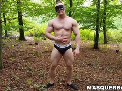 Muscular dude strokes his cock outdoors while wearing a mask